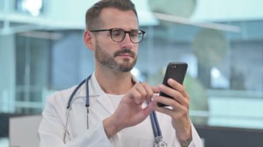 Orta yaşlı erkek doktor akıllı telefon kullanıyor.