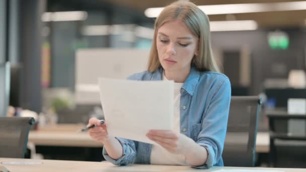 Jeune femme lisant des documents au bureau — Video