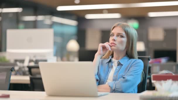 Junge Frau sitzt im Büro und denkt nach — Stockvideo