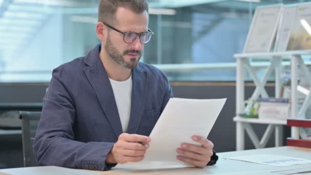 Middeleeuws zakenman die documenten leest terwijl hij op kantoor zit — Stockvideo