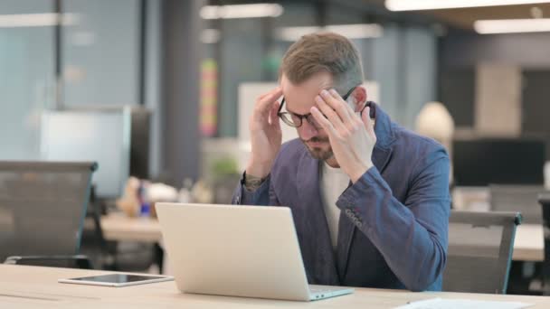 Empresario de mediana edad con dolor de cabeza Trabajando en el ordenador portátil en la oficina — Vídeos de Stock