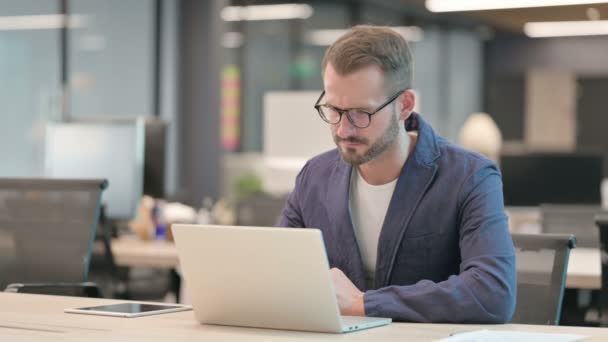 Imprenditore di mezza età che reagisce alla perdita durante l'utilizzo del computer portatile in ufficio — Video Stock