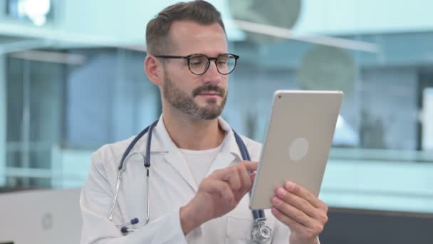 Мужской врач среднего возраста просматривает Интернет на планшете — стоковое видео