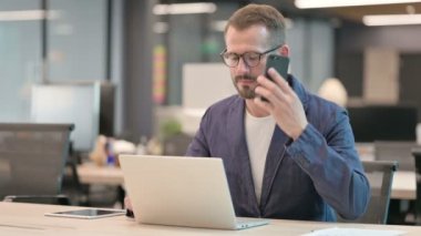 Orta Çağ İşadamı Laptop kullanırken Smartphone ile konuşuyor 