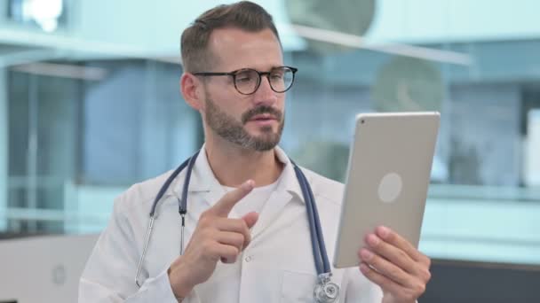 Orta yaşlı erkek doktor tablete video çağrısı yapıyor — Stok video