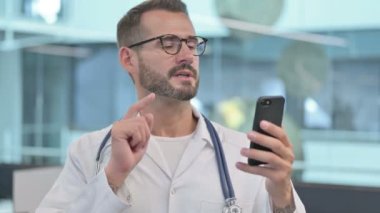 Orta yaşlı erkek doktor Smartphone 'da video çağrısı yapıyor. 