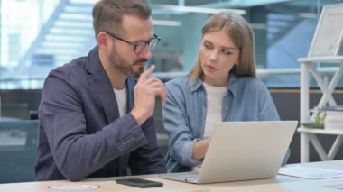 İşadamı ve İş Kadını Ofisteki Dizüstü bilgisayarda tartışıyorlar