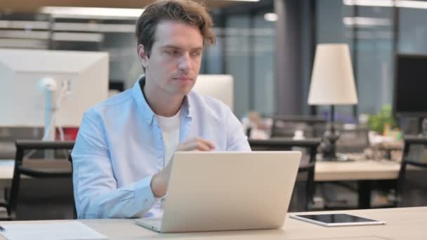Man Thinking podczas pracy na laptopie w biurze — Wideo stockowe
