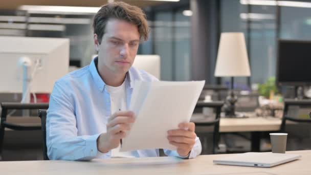 Hombre molesto mientras lee documentos en la oficina — Vídeos de Stock