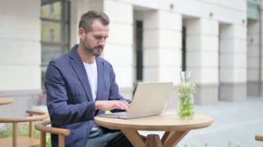 Laptop kullanırken İşaret Yok yazan bir adam, Açık Cafe 'de oturuyor