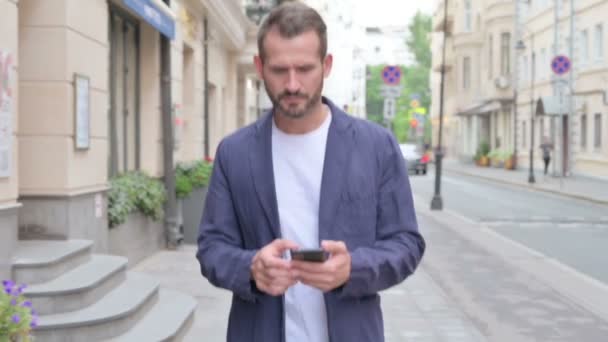 Man Browsing Internet na Smartphone, zatímco procházky po ulici, pomalý pohyb — Stock video