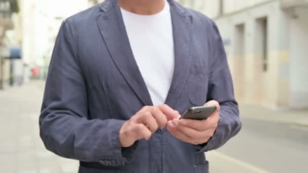 Nahaufnahme eines Mannes, der beim Gehen mit dem Smartphone im Internet surft — Stockvideo