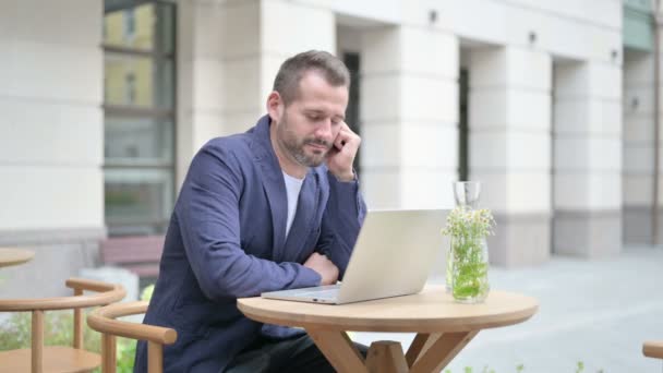 Hombre que se queda dormido mientras usa el ordenador portátil, sentado en el café al aire libre — Vídeos de Stock