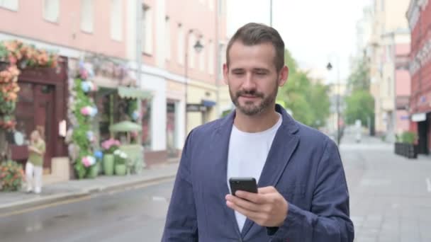 Ο άνθρωπος που χρησιμοποιεί το τηλέφωνο, ενώ το περπάτημα στην όμορφη οδό — Αρχείο Βίντεο