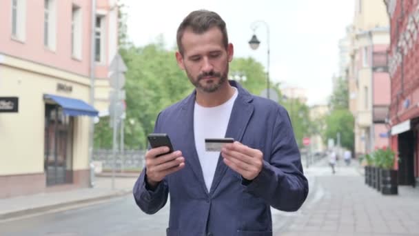 Hombre que tiene fallo de pago en línea en el teléfono inteligente mientras camina por la calle — Vídeos de Stock