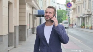 Sokakta yürürken telefonda konuşan adam.