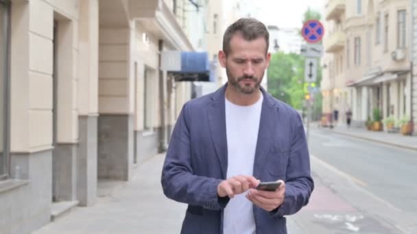 Man Browsing Internet on Smartphone while Walking in Slow Motion — Stock Video