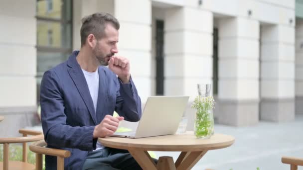 Man Coughing while using Laptop, Sitting in Outdoor Cafe — Stock Video