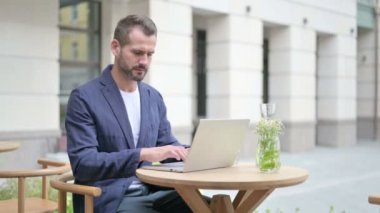 Laptop kullanırken Kameraya Bakan Adam Açık Cafe 'de Oturuyor