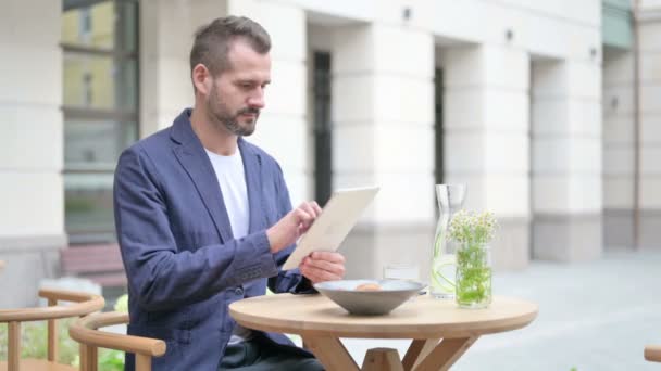 Hombre hojeando Internet en la tableta mientras está sentado en el café al aire libre — Vídeos de Stock