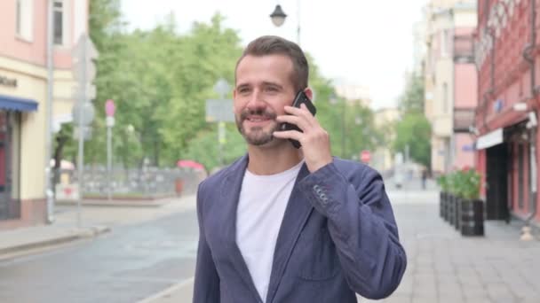 Homem conversando no telefone enquanto caminhava na bela rua — Vídeo de Stock