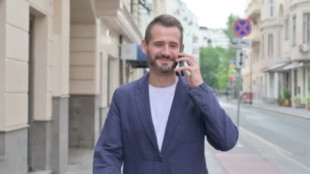 Ο άνθρωπος που παρακολουθεί τηλεφωνική κλήση, ενώ το περπάτημα στην όμορφη οδό — Αρχείο Βίντεο