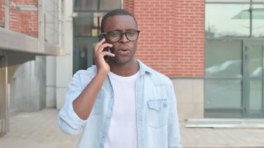 Sokakta yürürken akıllı telefonda konuşan Afrikalı adam. 