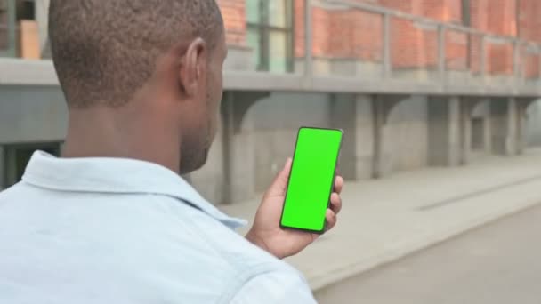 Camminare uomo africano utilizzando Smartphone con schermo verde — Video Stock