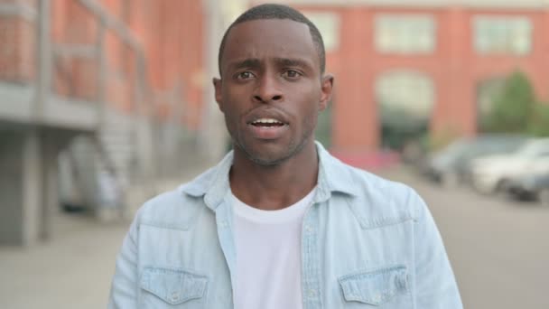 Utomhusporträtt av spännande afrikansk man som reagerar på förlust — Stockvideo