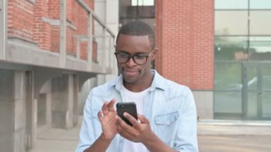 Sokakta yürürken akıllı telefon kullanan Afrikalı adam