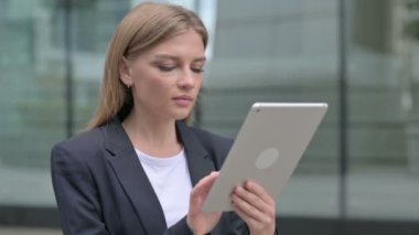 Sokakta yürürken tablet kullanan çekici genç iş kadını. 