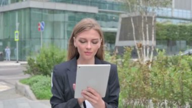 Sokakta yürürken tablet kullanan çekici genç iş kadını. 
