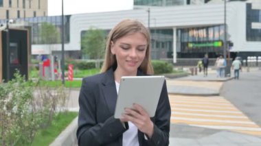 Sokakta yürürken tablet kullanan çekici genç iş kadını. 