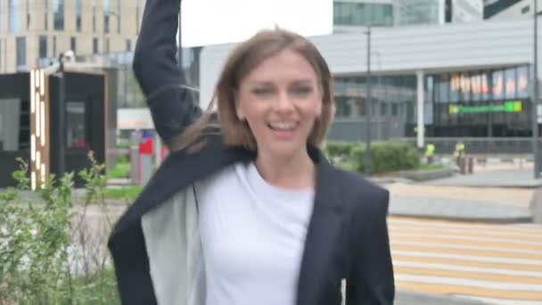 Молодая предпринимательница танцует в радости, гуляя по улице — стоковое видео
