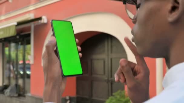 Achteraanzicht van Afrikaanse Man Kijkend naar Smartphone met Green Chroma Screen — Stockvideo