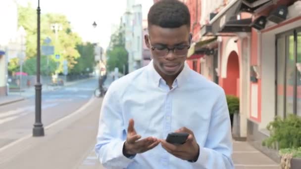 Lopende Afrikaanse Man reageert op verlies op Smartphone — Stockvideo
