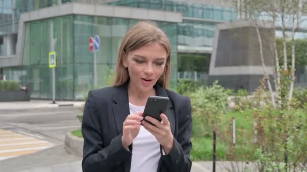 Młoda Bizneswoman świętuje sukces na smartfonie podczas spaceru po ulicy — Wideo stockowe