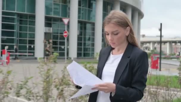 Молодая предпринимательница читает документ во время прогулки по улице — стоковое видео