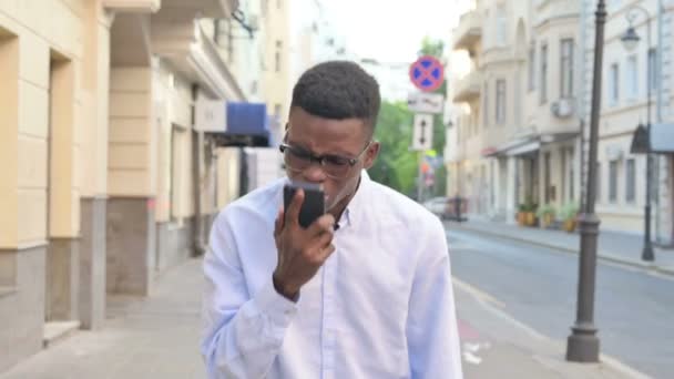 Afrikaanse man krijgt boos op oproep tijdens het lopen op straat — Stockvideo