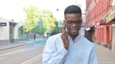 Sokakta yürürken telefonda konuşan Afrikalı adam.