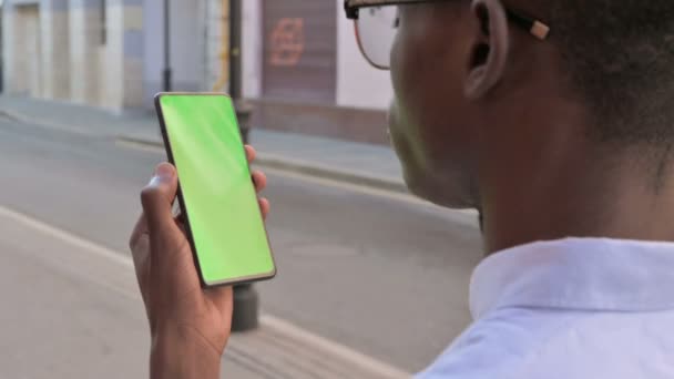 Achteraanzicht van Afrikaanse Man Kijkend naar Smartphone met Green Chroma Screen — Stockvideo