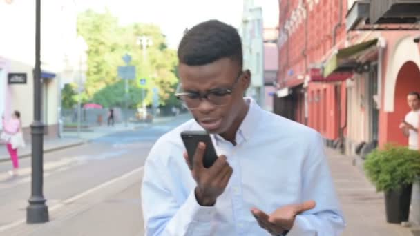 Afrikaanse man krijgt boos op oproep tijdens het lopen op straat — Stockvideo
