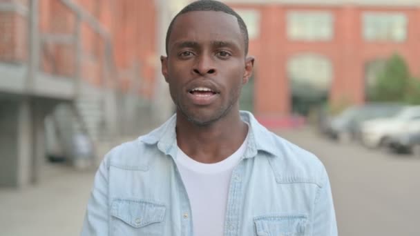 Retrato al aire libre del hombre africano mostrando un signo silencioso por dedo en los labios — Vídeo de stock