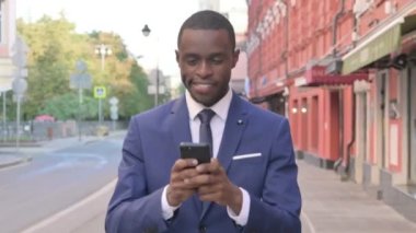Sokakta Yürürken Akıllı Telefon kullanan Afrikalı İşadamı