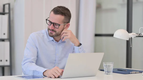 Moyen Age Homme se sentant en colère tout en travaillant sur ordinateur portable — Photo