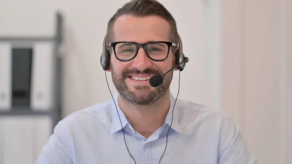 Portret mężczyzny w średnim wieku z słuchawkami uśmiechniętymi do aparatu — Zdjęcie stockowe