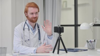 Kızıl saçlı erkek doktor Smartphone 'da görüntülü konuşma yapıyor.