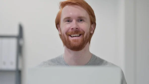 Homem ruivo barba com laptop sorrindo para a câmera — Fotografia de Stock