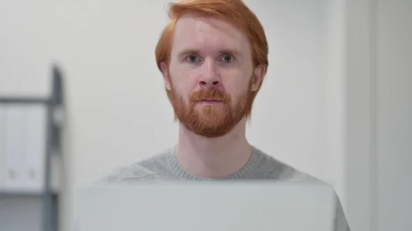 Homem ruivo barba com laptop olhando para a câmera — Fotografia de Stock