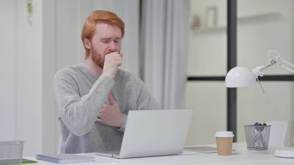 Beard Redhead Man Coughing while working on Laptop